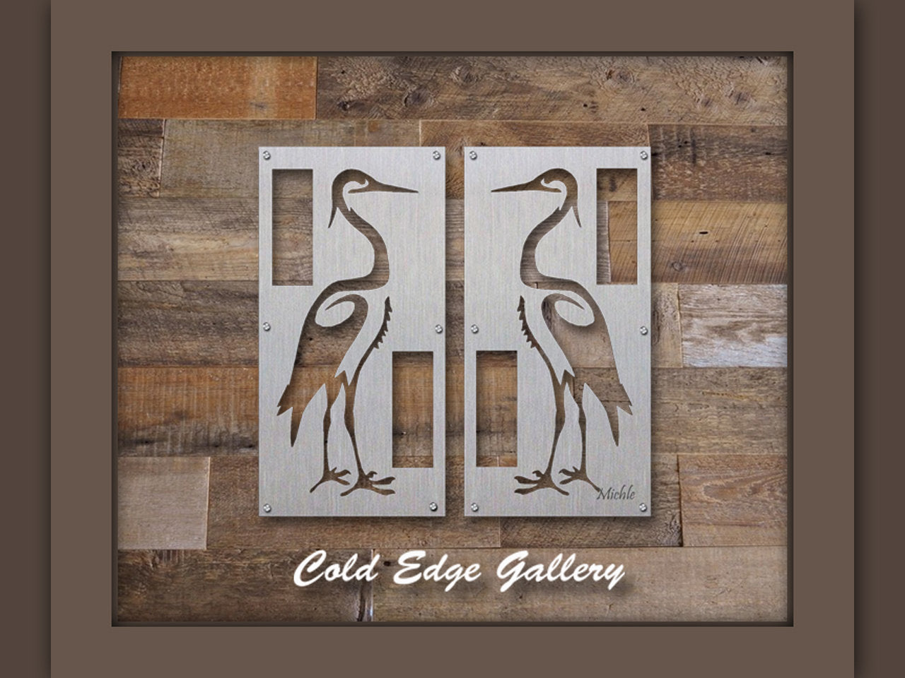 Two metallic panels featuring heron designs are mounted on a wooden wall and framed with a dark border, labeled "Cold Edge Gallery" at the bottom.