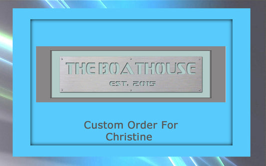 A metal plaque with the text "THE BOATHOUSE EST. 2015" inside a grey and blue frame. Below, in blue, are the words "Custom Order For Christine". This custom artwork perfectly blends functionality and elegance.