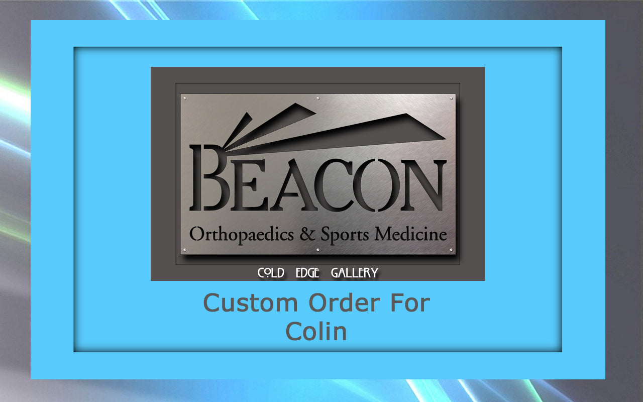 A silver plaque with "Beacon Orthopaedics & Sports Medicine" and "Cold Edge Gallery" engraved, set in a blue frame, showcasing exquisite custom metal artwork with the text "Custom Order For Colin" at the bottom.