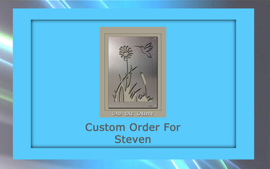 A custom metal wall panel featuring an intricate floral and bird design is displayed. The text "Custom Order For Steven" appears beneath the stunning artwork, which is bordered by a blue frame.