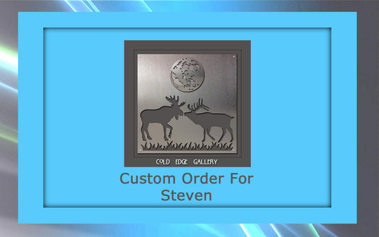 A metal art piece featuring two deer with antlers facing each other under a full moon. The text reads "Cold Edge Gallery" and "Custom Order For Steven.