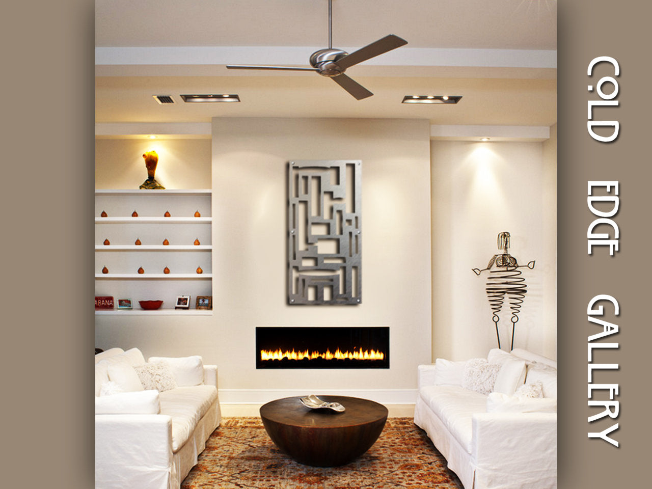 Modern living room with white sofas, a round wooden coffee table, and built-in shelves flanking a wall-mounted fireplace. Artwork and a sculptural figure decor are on display, with "Cold Edge Gallery" text overlay.