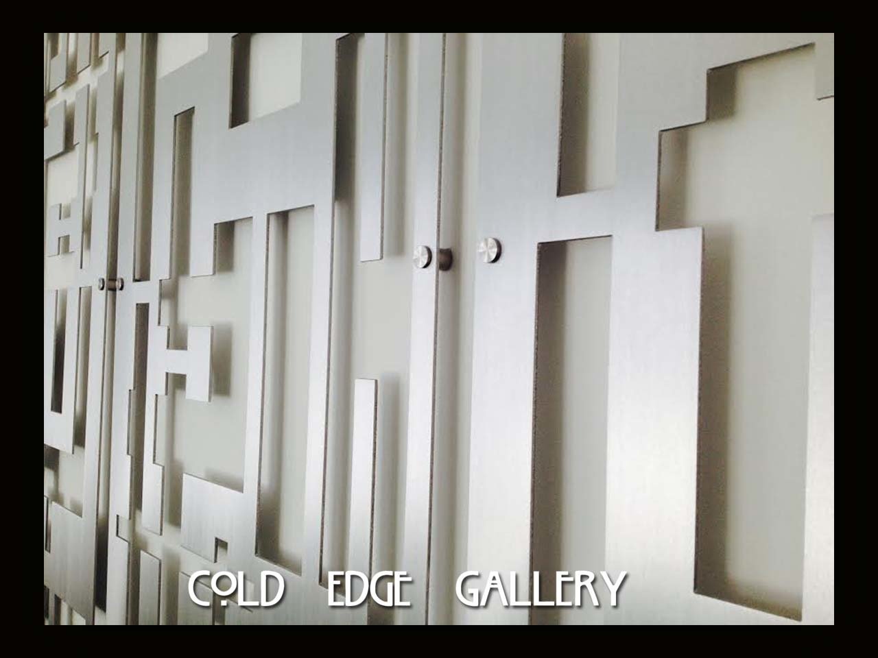 Abstract metallic wall art with geometric cutouts and a reflective surface, captioned "Cold Edge Gallery" at the bottom.