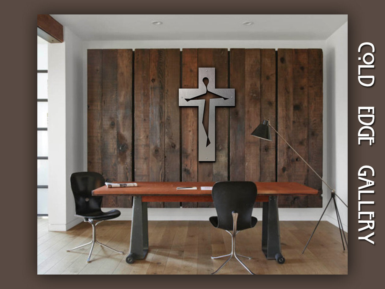 An office space with a wooden desk and two chairs. A metal cross decor is displayed on a wooden panel wall. A floor lamp is on the right. The words "Cold Edge Gallery" are on the side.