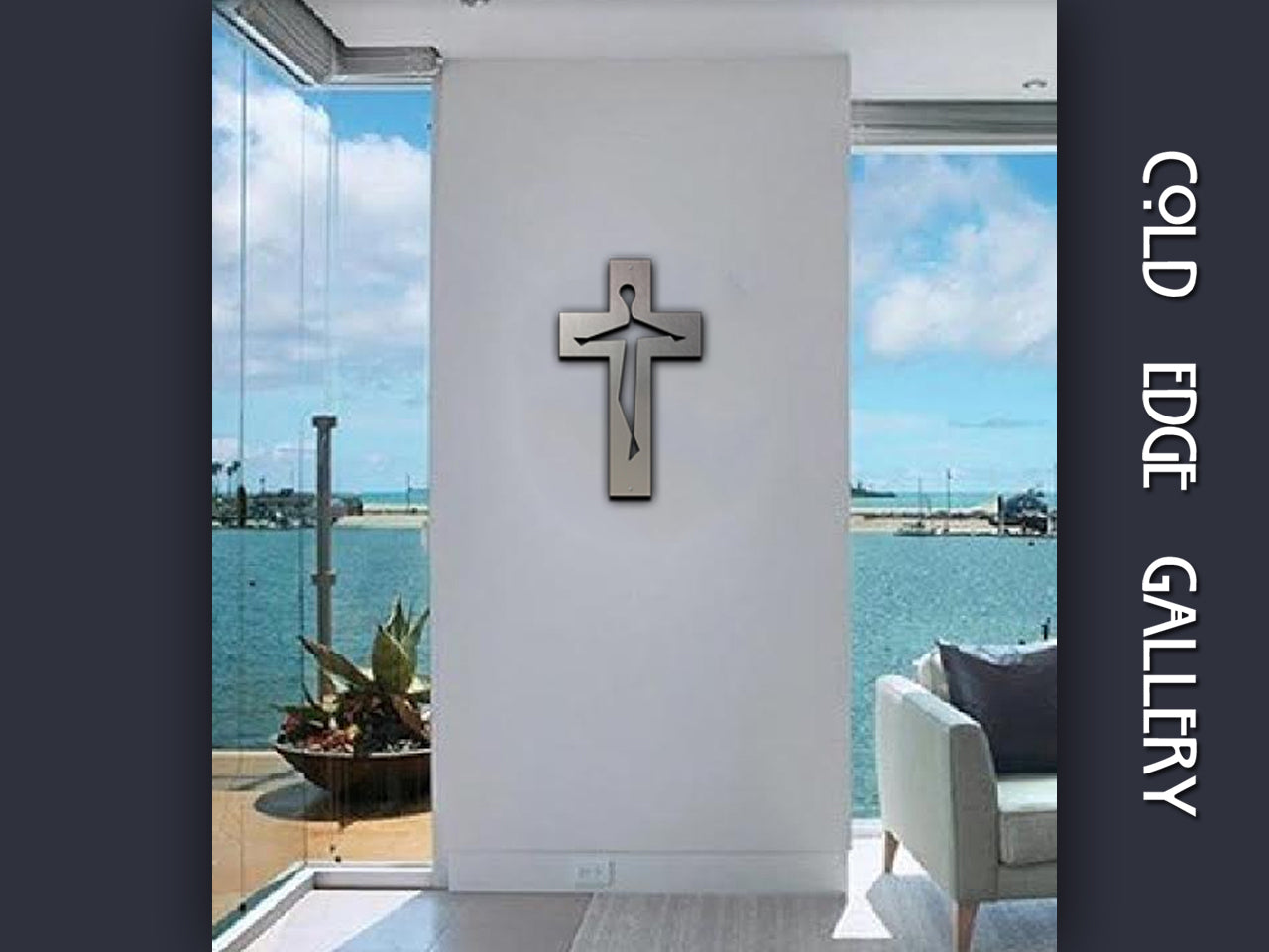 A modern metal cross with a minimalist design hangs on a white wall in a bright room overlooking a body of water, with the text "COLD EDGE GALLERY" written vertically on the image's right side.