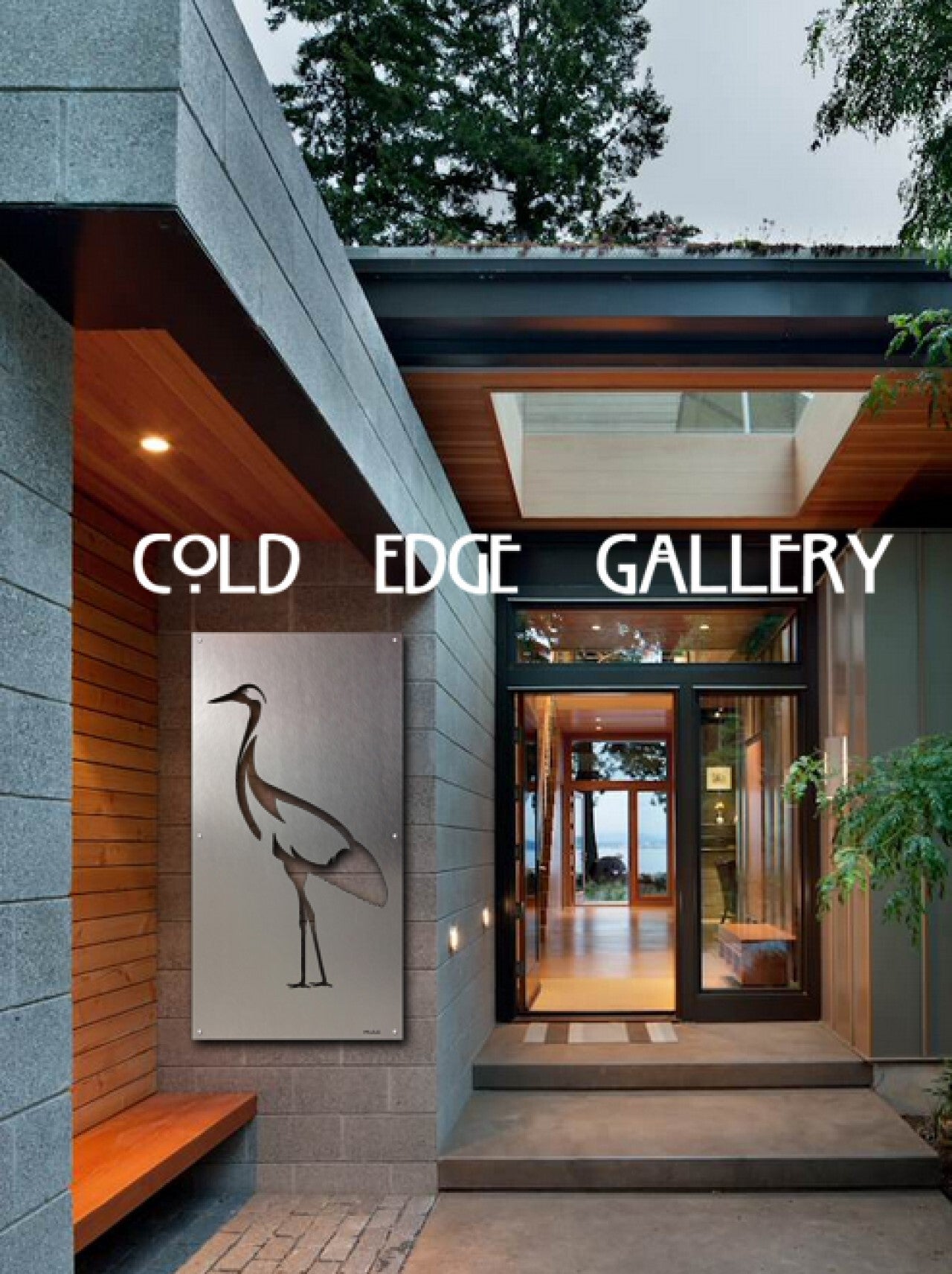 Entrance of Cold Edge Gallery with modern architectural design, large glass windows, and a metal artwork of a bird on the concrete wall. The interior of the gallery is visible through the glass door.