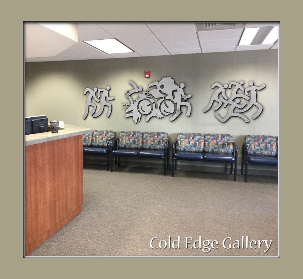 Reception area with a wooden desk, patterned seating, and metal wall art featuring human-like figures in various poses. Text in the bottom right corner reads "Cold Edge Gallery.